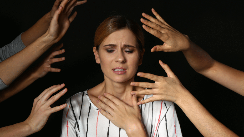 A woman and people's hands around her, representing social anxiety